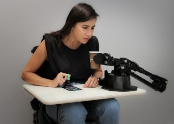 A member of the ALYN Hospital team demonstrates the use of a robotic arm designed to assist patients with spinal injuries in performing daily tasks. Using funding and technology support from Accenture, as well as Intel’s neuromorphic technology, researchers from the Open University of Israel and ALYN Hospital will refine the device and clinically evaluate it with pediatric patients. (Credit: ALYN Hospital)