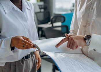 Photo by Mikhail Nilov: https://www.pexels.com/photo/colleagues-standing-in-white-long-sleeve-shirts-discussing-and-reading-a-financial-report-8297478/